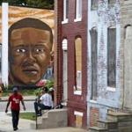 FILE - In this June 23, 2016 file photo, a mural depicting Freddie Gray is seen past blighted row homes in Baltimore, Thursday, June 23, 2016, at the intersection where Gray was arrested. Gray later died in police custody. An Associated Press review of court records nationwide shows that the attorneys who represent cities are sometimes weak links in the systems meant to hold police accountable for wrongdoing. The review found that lawyers deliberately hid important facts, delayed their disclosure or otherwise sought to subvert evidence in civil cases. (AP Photo/Patrick Semansky, File)
