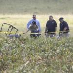 The partial frame of a hot air balloon is visible above a crop field as investigators combed the wreckage of a crash Saturday morning near Lockhart, Texas.
