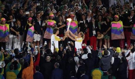 epa05457862 Brazilian tennis legend Gustavo Kuerten (L) hands the Olympic flame to Hortencia Marcari (R) during the Opening Ceremony of the Rio 2016 Olympic Games at the Maracana Stadium in Rio de Janeiro, Brazil, 05 August 2016. EPA/HOW HWEE YOUNG
