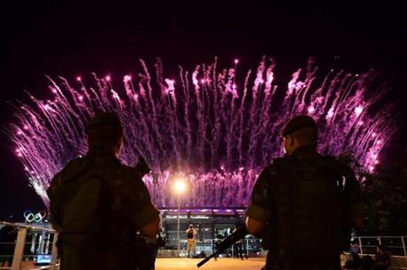 Brazilian security forces stand guard outside the Maracana stadium as fireworks explode during Opening Ceremony of the Rio 2016 Olympic Games.
