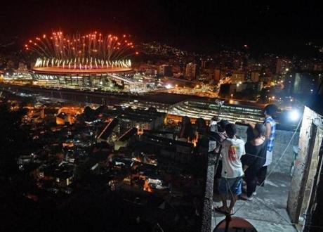 People watch fireworks exploding over the Maracana stadium, from a terrace in the favela Mangueira, during the Opening Ceremony of the Rio 2016 Olympic Games.
