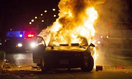 A car burns as a crowd of more than 100 people gathers following the fatal shooting of a man in Milwaukee on Saturday.
