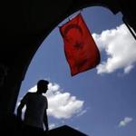 A pedestrian passes under a Turkish flag in Istanbul, Sunday, Aug. 14, 2016. Turkish authorities have prepared an official request for the temporary arrest of United States-based Islamic cleric Fethullah Gulen over his alleged involvement in the coup attempt on July 15, Turkey's state-run Anadolu news agency said Saturday. (AP Photo/Thanassis Stavrakis)