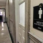 Visitors walked past a men?s bathroom while exiting the State House in Boston earlier this year.