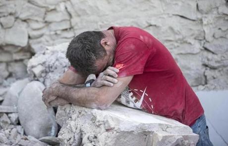A man leaned on the rubble of buildings in Amatrice, Italy.
