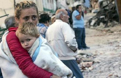 A woman held a child while standing on a street in Amatrice.
