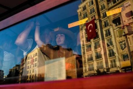 A woman looks on while riding the tramway as Turkey?s flag is reflected in the window in Taksim square in Istanbul on July 22, following the failed military coup attempt of July 15. 
