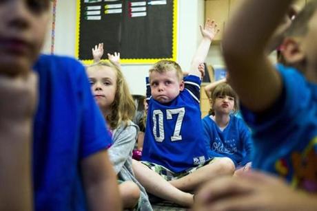 First-grader Dominik Rosebush, 6, center, raises his hand, trying to get teacher Mindy Parrott to call on him for the answer to a question as students attend their first day of school on Aug. 22 at Central Elementary School in Davison. 
