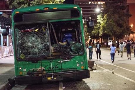 CHARLOTTE, NC - SEPTEMBER 22: Demonstrators walk near a damaged bus on September 22, 2016 in downtown Charlotte, NC. The North Carolina governor has declared a state of emergency in the city of Charlotte after clashes during protests in the city in response to the fatal shooting by police officers of 43-year-old Keith Lamont Scott at an apartment complex near UNC Charlotte. (Photo by Sean Rayford/Getty Images)
