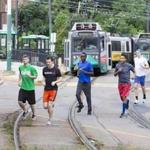 A group of runners began their race against an MBTA Green line train along Commonwealth Avenue in Boston.