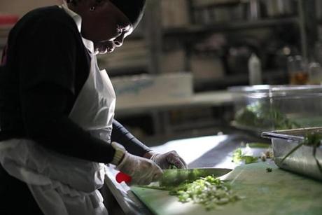 Lincoln/Boston, MA., 10/05/16, Lisa Edwards is an iCater trainee in the Pine Street Inn kitchen and she is chopping the freshly picked scallions. The Cambridge nonprofit Food for Free grows fresh produce at Lindentree Farm specifically for the Pine Street Inn, which is allowing homeless patrons to regularly eat high-quality fresh veggies. Volunteers harvest the produce. Globe staff/ Suzanne Kreiter
