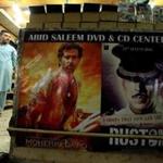 A man stands in a DVD shop in Rawalpindi, Pakistan, near a display of Bollywood movies.