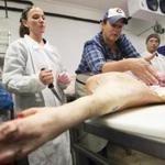 Kari Underly (center) demonstrates hog butchering at the Women in Meat Northeast conference.