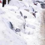 A line of cars sit buried in snow banks in Somerville, Mass., Tuesday, Feb. 10, 2015. The latest snowstorm left the Boston area with another two feet of snow and forced the MBTA to suspend all rail service for the day. (AP Photo/Josh Reynolds)