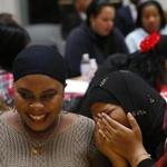 Boston, MA -- 11/15/2016 - Jawaher Noor, of Quincy (R) who is originally from Somalia laughs on the shoulder of Nechka Mars, of Hyde Park who is originally from Haiti, as one of the women at her table sketches a portrait of her during MIRA's 12th Annual Thanksgiving Luncheon at the State House. (Jessica Rinaldi/Globe Staff) Topic: 15mira Reporter: 