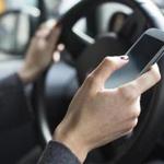 Hands of a woman using her mobile phone while driving.