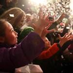 Riley Donlon, 8, reached out to catch a piece of confetti during the lighting of the Christmas tree on top of Macy?s in Downtown Crossing Friday.