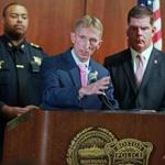 Boston Police Commissioner William Evans is pictured at the podium, with Boston Mayor Martin Walsh at right and Boston Police Superintendent-In-Chief William Gross at left.