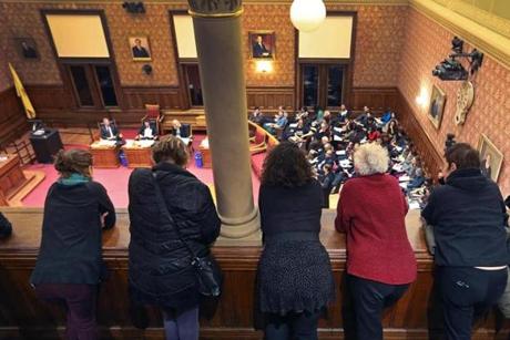 Cambridge, MA- 11-21-16: People watch and listen from above as an overflow crowd attended a Cambridge City Council Meeting this evening. Many residents spoke to the council supporting the continuation of Cambridge as a 