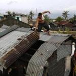 epa05688401 A Filipino villager reinforces a damaged roof in the typhoon-hit town of Pamplona, Camarines Sur, Philippines, 26 December 2016. According to an Office of Civil Defense (OCD) report on 26 December, hundreds of thousands of villagers spent their Christmas day in evacuation centers in Bicol region, many flights were cancelled at Manila's international airport, and scores of sea vessels have reportedly sunk as Typhoon Nock-ten brought howling winds and strong rains in central Philippines. EPA/FRANCIS R. MALASIG