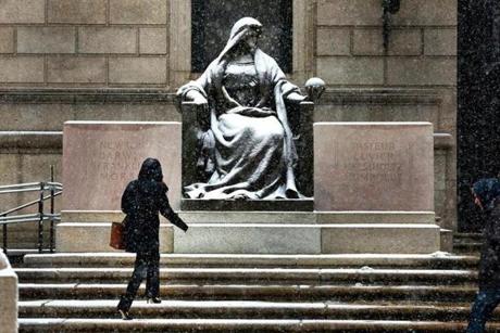 Snow fell on a statue located on the steps of the Boston Public Library in Copley Square in January 2015. 
