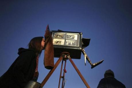 In this Sept. 4, 2016 photo, a woman looks through the viewfinder of the old wooden box camera used by photographer Luis Maldonado during a fair marking Independence Day in Santiago, Chile. Chile's box photographers union had more than 5,000 members by 1942, but that number plunged to about 300 by 1972, according to Chilean historian Octavio Cornejo. (AP Photo/Esteban Felix)
