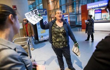 Protester Amanda Shepard passed out signs that read ?No Ban No Wall No Division? at Boston Logan Airport Saturday. 
