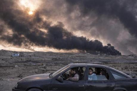 A family flees fighting as oil fields burn in Qayyara, Iraq, Nov. 12, 2016. The military campaign to retake Mosul, Iraqâ??s second-largest city, has displaced nearly 70,000 Iraqis. More civilians than ever are taking the risk of evacuation, hoping to find help if they can make it past the militantsâ?? gun range. (Sergey Ponomarev/The New York Times)
