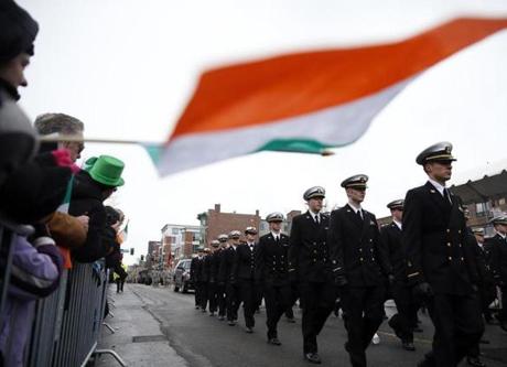 A person held out an Irish flag as members of the Regimental Band and Honor Guard from Massachusetts Maritime Academy marched during 2015?s St. Patrick's Day Parade in South Boston.
