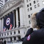 A woman wearing a Canada Goose coat stops to photograph the company's banner at the New York Stock Exchange on Thursday. 