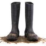 Muddy rubber boots front view isolated on white background