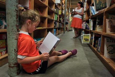 A young girl reads a book at the New England Mobile Book Fair in Newton Highlands in 2013.
