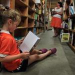 A young girl reads a book at the New England Mobile Book Fair in Newton Highlands in 2013.