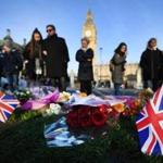 epa05868191 People stand by to look at flowers and Union jack flags placed on Parliament square by well-wishers in London, Britain, 24 March 2017. Well-wishers have flocked to the scene of the 22 March terror attack to pay their respects to those killed in the attack. Scotland Yard said on 24 March 2017 that police have made nine arrests in relation to the terror attack in the Westminster Palace grounds and on Westminster Bridge on 22 March 2017 leaving at least five people dead, including the attacker, and 29 people injured. EPA/ANDY RAIN