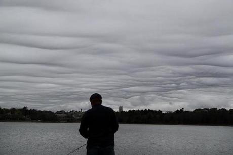 Before the rain came in, clouds hung over the Chestnut Hill Reservoir as a man went fishing. 
