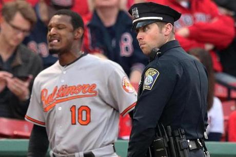 A police officer stood outside the Orioles' dugout as Adam Jones (10) headed for the on-deck circle before the start of the game. 
