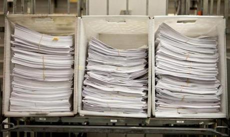 Piles of 2012 paper tax returns to be sorted through are seen in the Data Integration Bureau of the Department of Revenue in Chelsea. 
