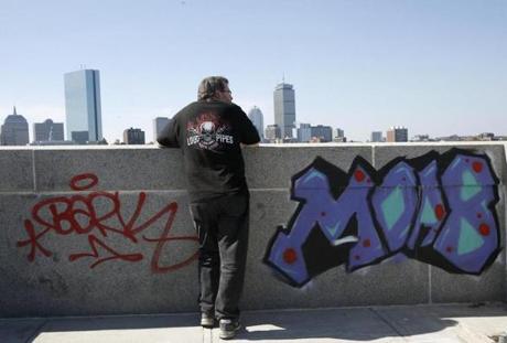 A man paused to look at the skyline next to graffiti scrawled on the Longfellow Bridge in Boston. 
