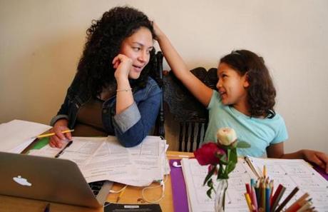 Ginnelle Vasquez, left, and her daughter Isis, 8, shared a joke while working on their homework at their home on June 8.  
