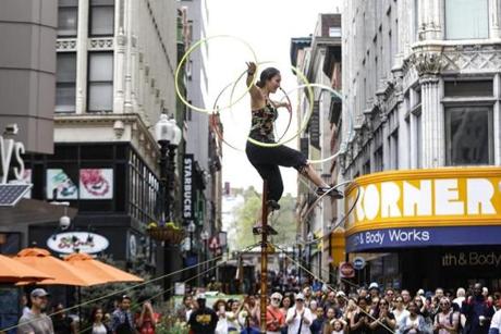 Street performer Sara Kunz juggled hula hoops from atop a pole for passersby in Downtown Crossing in Boston.
