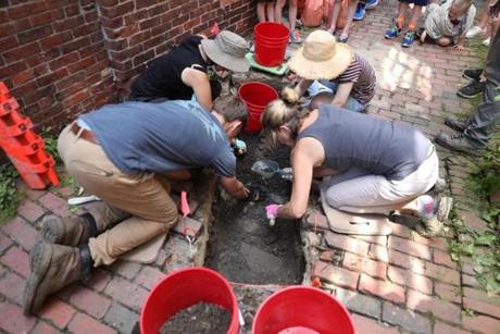 Boston, MA - 7/10/2017 - Joe Bagley (cq) (not shown), archaeologist for the City of Boston, leads a dig in the North End next to the Pierce-Hichborn House (cq). Volunteers work in the first exploratory trench dug today, where a wooden building formerly stood around 31 North Square. Tourists watch the activity. Photo by Pat Greenhouse/Globe Staff Topic: 11paulrevere Reporter: Emily Sweeney
