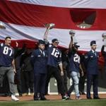 Boston, Massachusetts -- 4/3/2017 - (L-R) New England Patriots Rob Gronkowski, quarterback Tom Brady, James White, and Dion Lewis hoist Vince Lombardi trophies as they come out to the field before the start of Red Sox Pirates during Opening Day at Fenway Park. () Topic: Reporter: