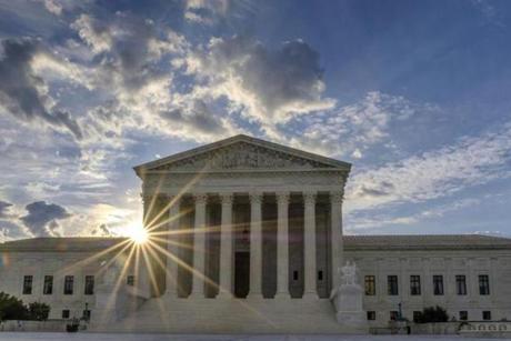 The sun flares in the camera lens as it rises behind the U.S. Supreme Court building in Washington, Sunday, June 25, 2017. The court is expected to decide within days if the Trump administration can enforce it's travel ban. (AP Photo/J. David Ake)
