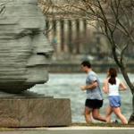 Two joggers passed by the memorial statue of Arthur Fiedler as they run along the Charles River near the Hatch Shell of the Esplanade.
