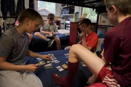 Orford, NH - 7/17/17 - Center, camper Carson Krulewitch, reads The Mark of Athena while his fellow campers play Magic the Gathering during a rainy afternoon at Camp Moosilauke on Monday, July 17, 2017. Because of the weather, the power was temporarily knocked out but campers continued on with flash lights, hardly missing a beat. (Nicholas Pfosi for The Boston Globe) Reporter: Tom Farragher Topic: 19Farragher

