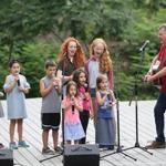 Tim McHale sings with kids from the audience at the Herter Park party.