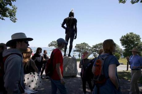 Visitors surround the statue of the Wampanoag leader Massasoit, which overlooks Plymouth Harbor.
