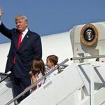 FILE- In this Aug. 4, 2017, file photo, President Donald Trump waves as he walks down the steps of Air Force One with his grandchildren, Arabella Kushner, center, and Joseph Kushner, right, after arriving at Morristown Municipal Airport to begin his summer vacation at his Bedminster golf club in Morristown, N.J. The president has decamped from Washington to his private golf club in central New Jersey. But he has repeatedly pushed back on the idea that this is a relaxing August getaway. (AP Photo/Evan Vucci, File)