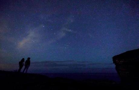 This picture taken on August 12, 2017 shows a couple enjoying Perseid meteor along the Milky Way illuminating the dark sky near Comillas, Cantabria community, northern Spain, during the 