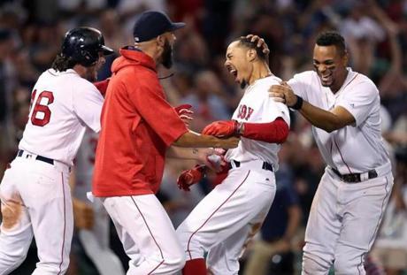 Boston, MA: August 16, 2017: The Red Sox Mookie Betts (second from right) is mobbed by teammates after his game winning The Boston Red Sox hosted the St. Louis Cardinals in a regular season inter league MLB baseball game at Fenway Park. (Jim Davis/Globe Staff). 
